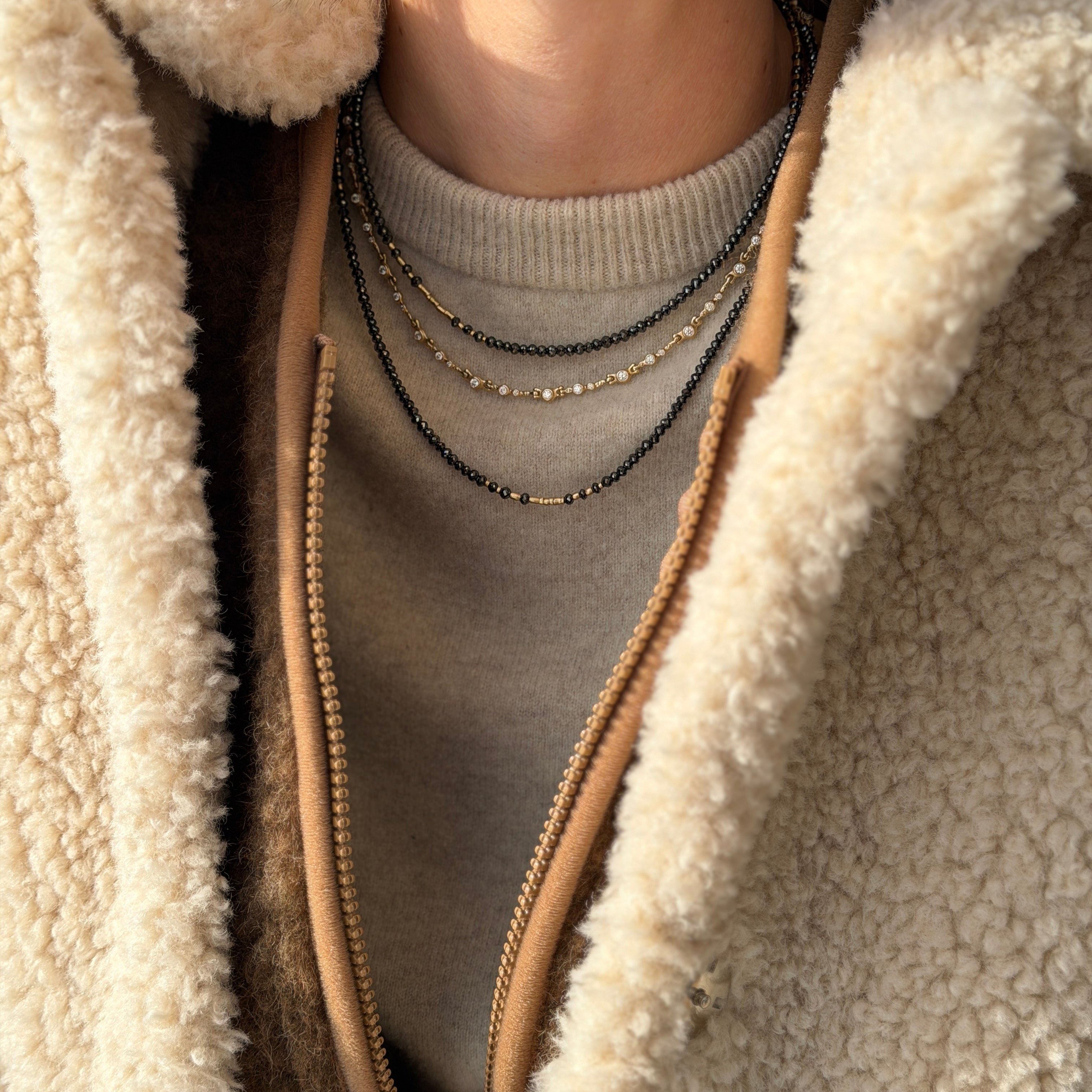 Woman with a fleece jacket on wearing 3 Audrius Krulis necklaces
