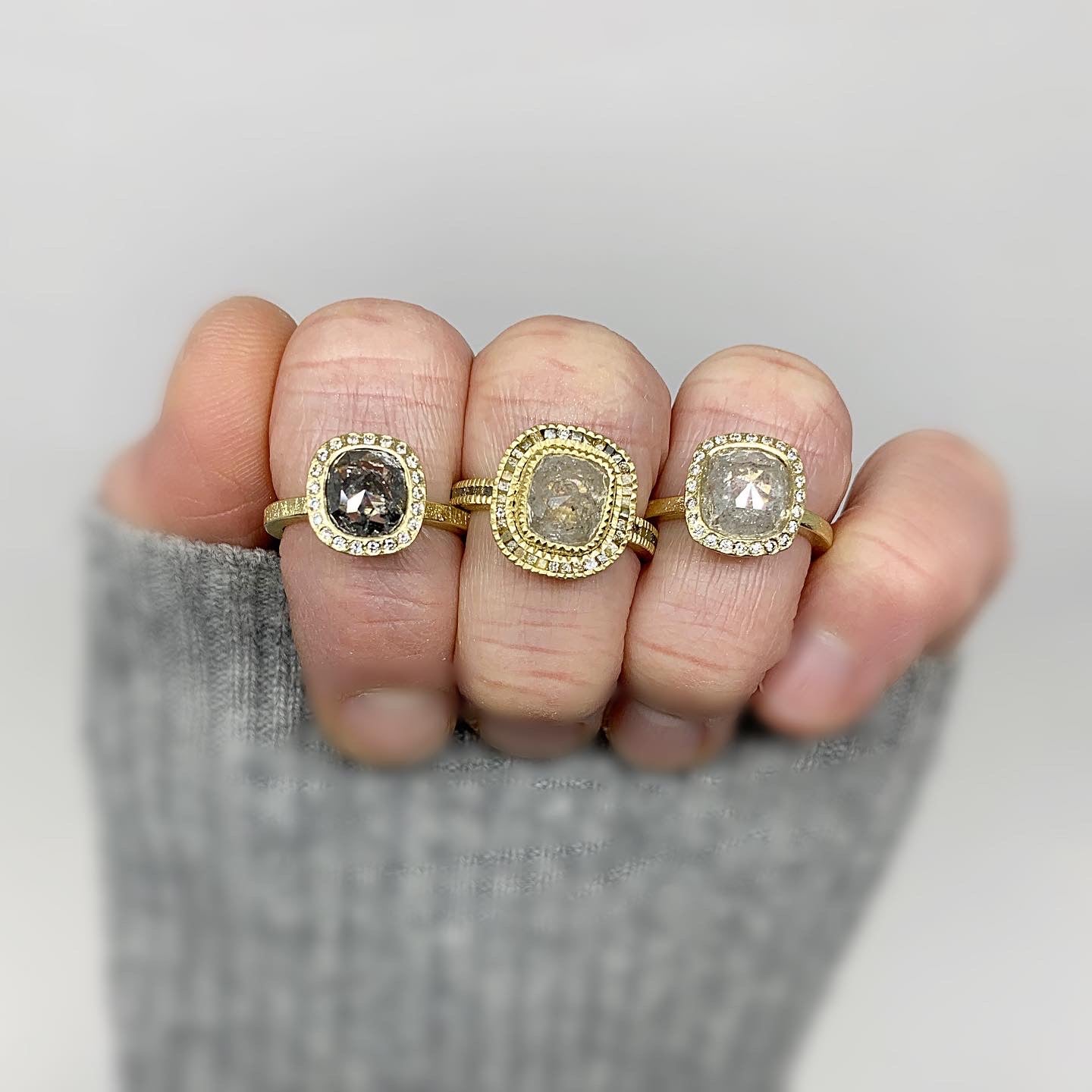 Hand in gray sweater with three rings on the fingers