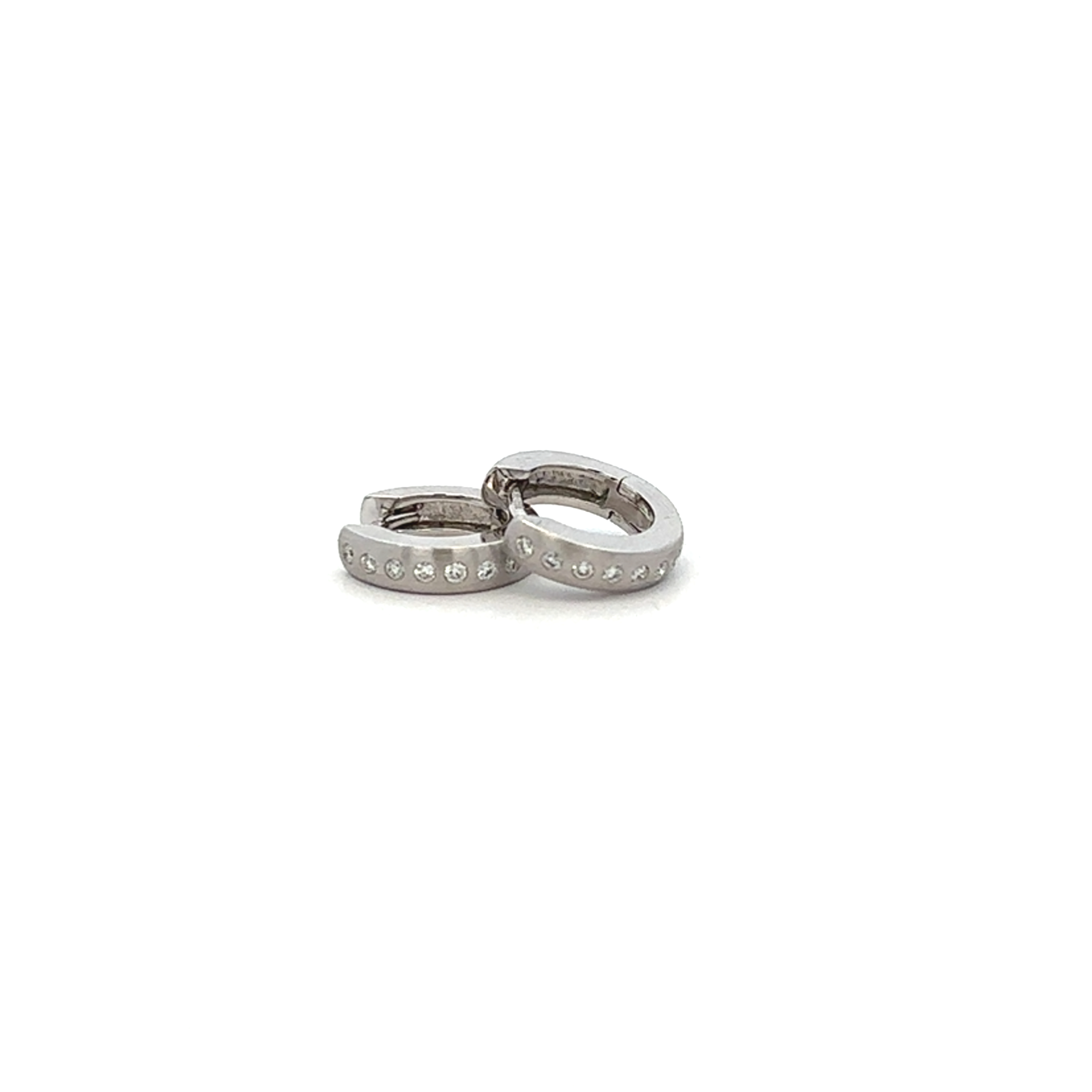 White Gold hoop earrings with diamonds embedded on a white background & surface