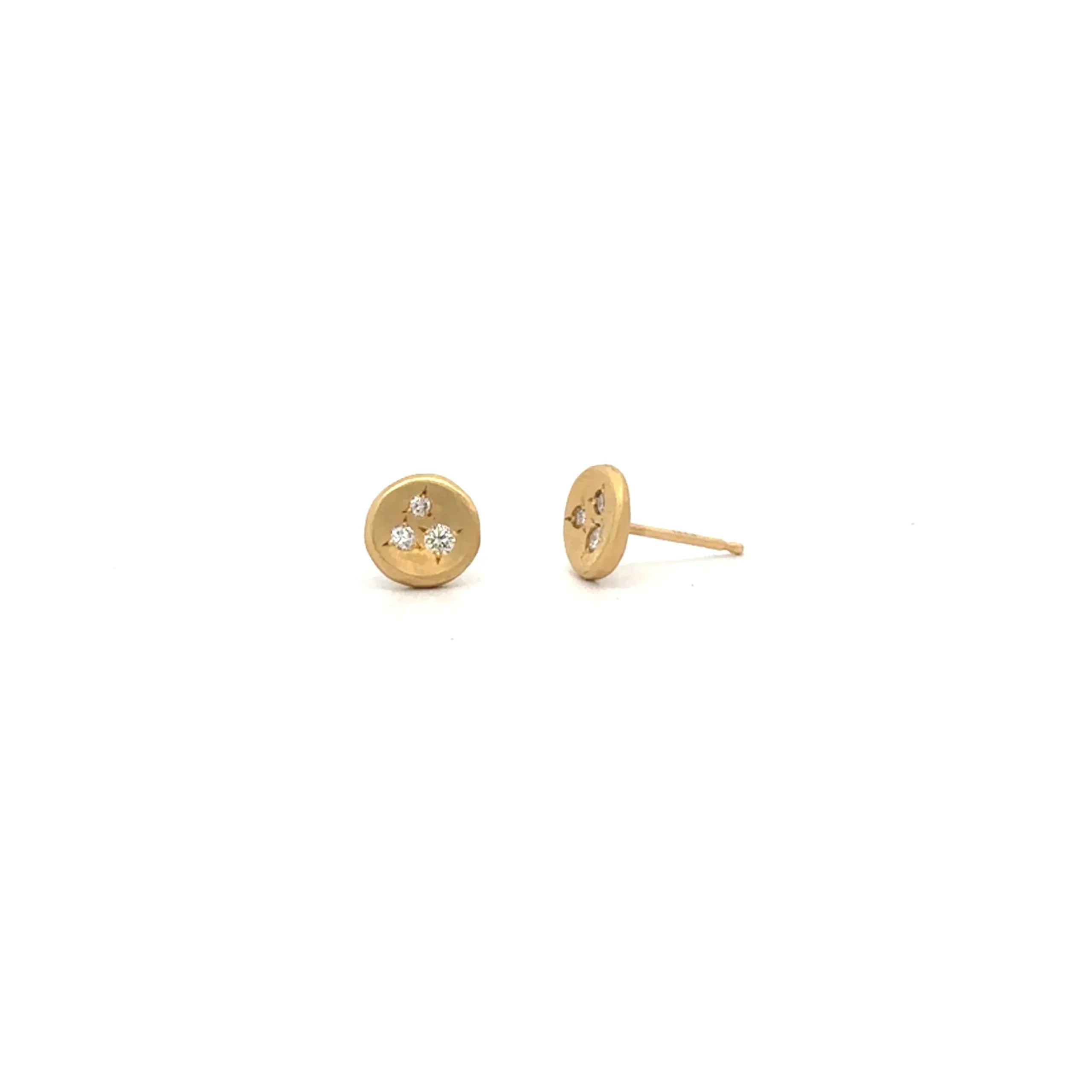 A pair of Ali Dumont Everyday Diamond Scatter Studs in small, round 18k yellow gold with three tiny diamonds arranged in a triangle. One earring is shown from the front, the other from the side to highlight the stud post.