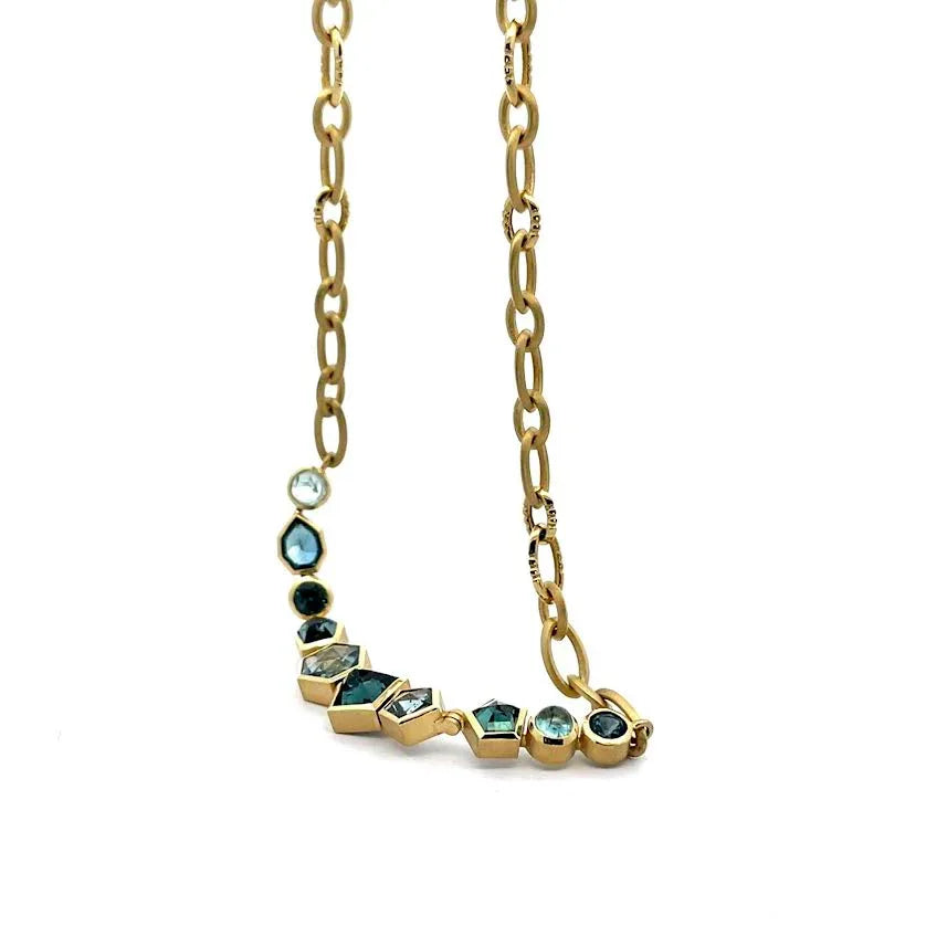 Gold necklace with green gemstones on a white background