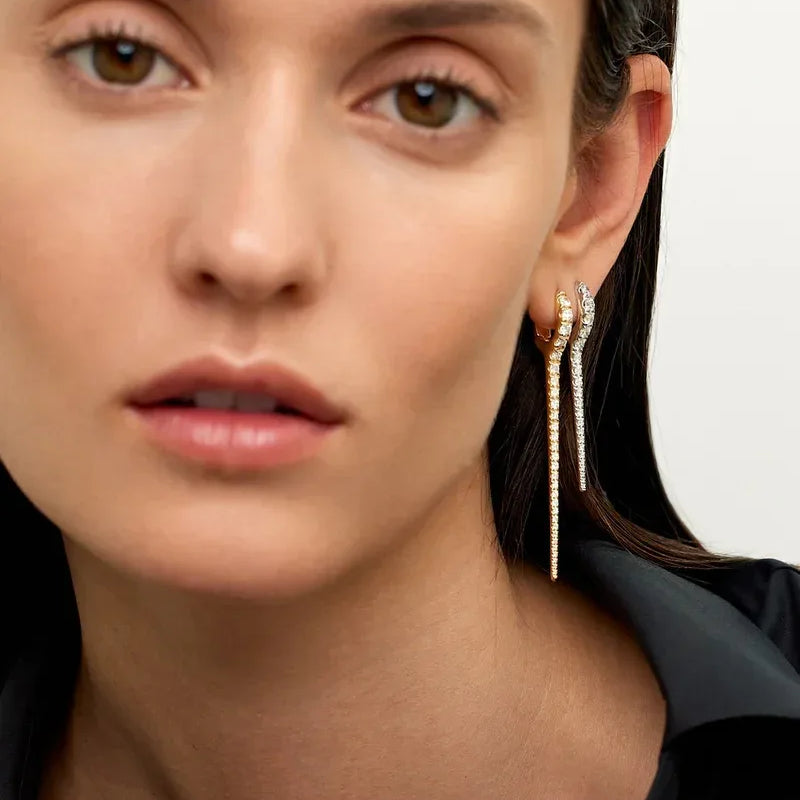 Close-up of a woman wearing gold earrings with a neutral background