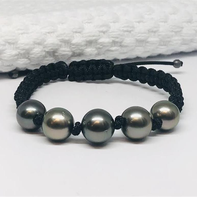 Black cord bracelet with five gray beads on a white background