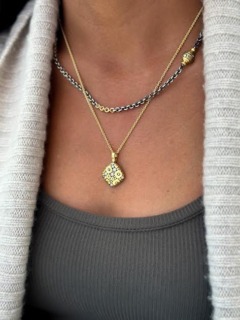 Woman in gray wearing two necklaces