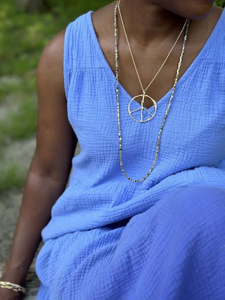 Woman in a blue dress with Gold necklaces and grass in the background