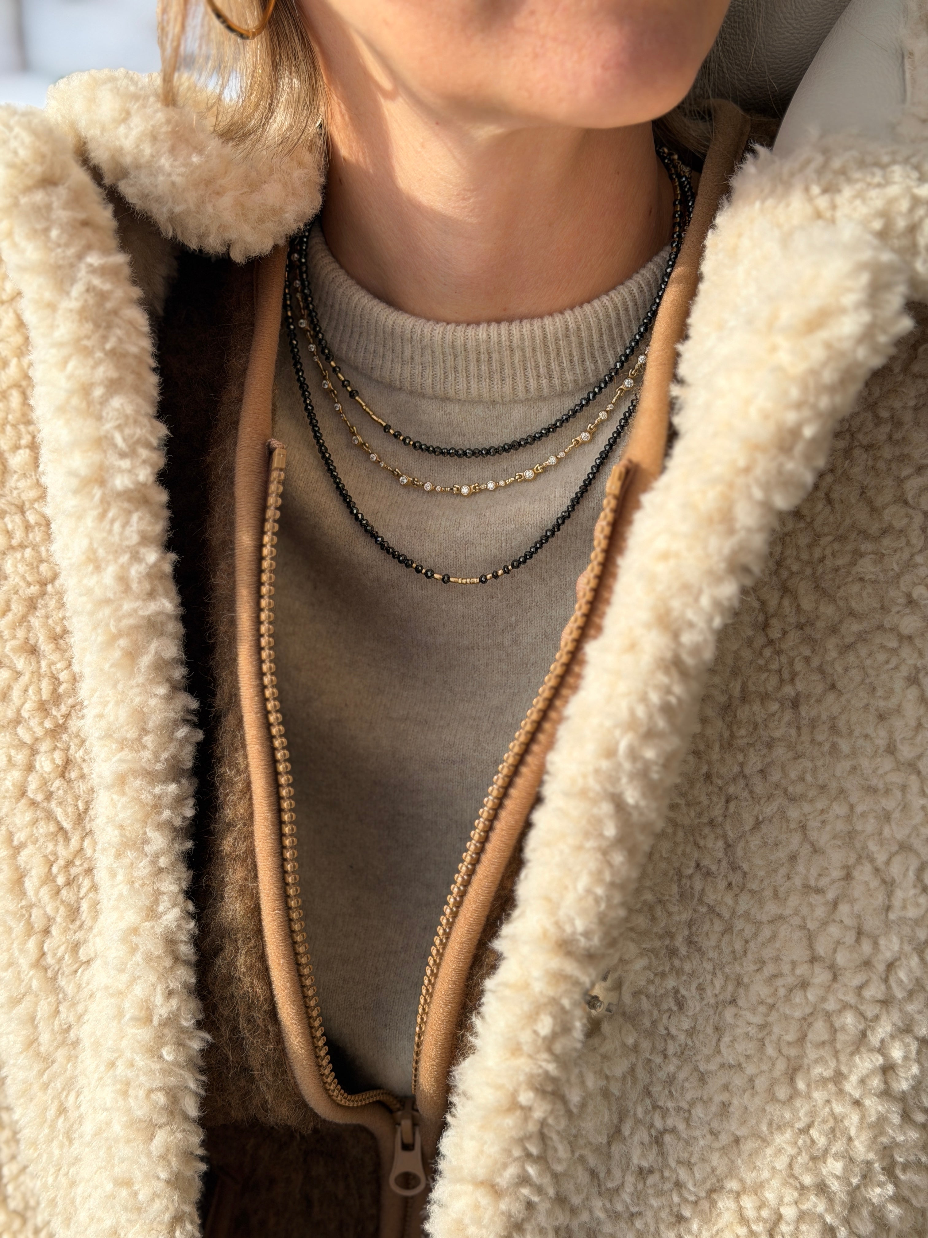Woman with a fleece jacket on wearing 3 Audrius Krulis necklaces
