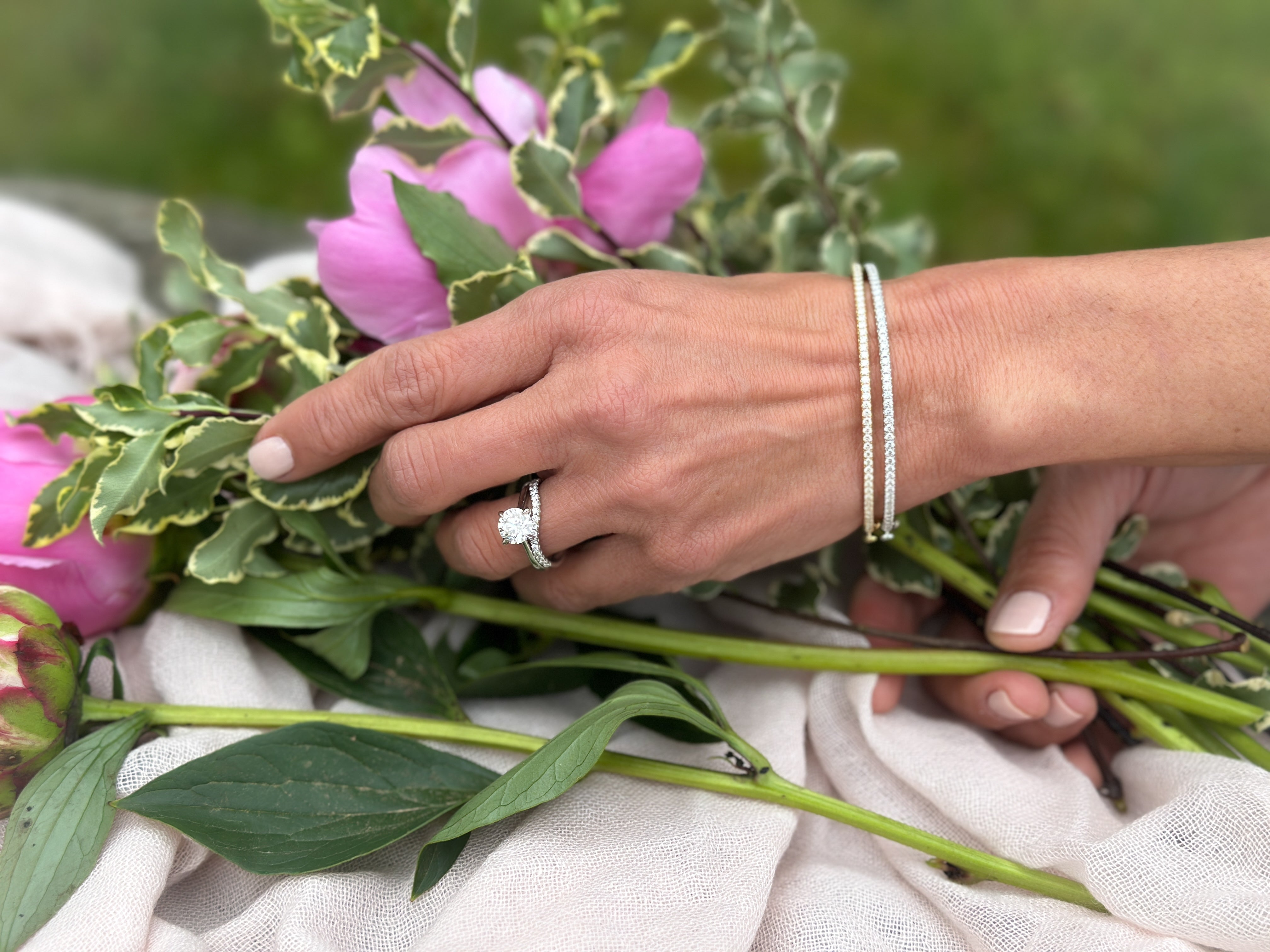 Woman working on a floral arrangement with pink flowers wearing Kwiat bracelets and ring