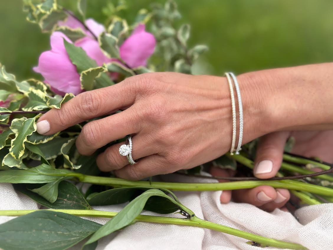 Hands wearing a ring and a bracelet holding flowers