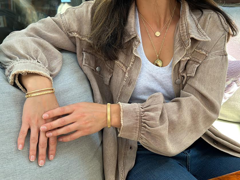 Woman in a brown jacket wearing multiple bands and a necklace