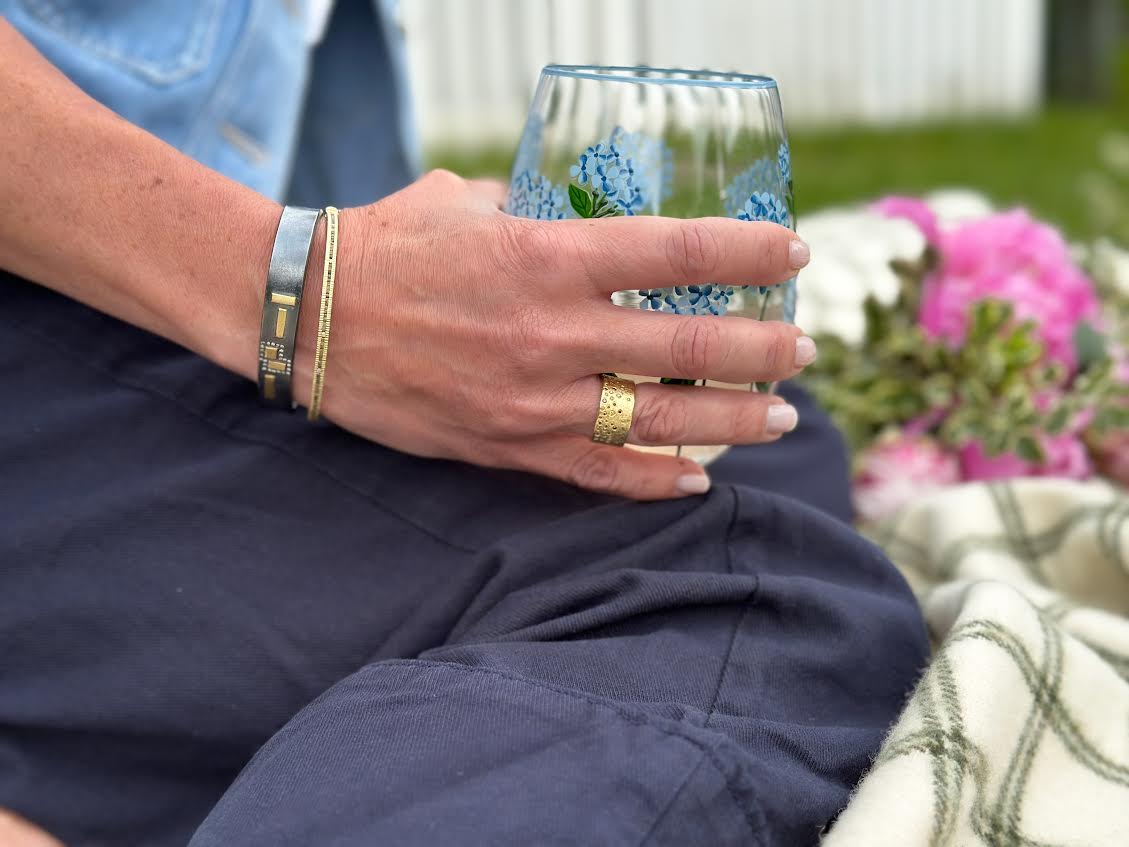 Hand with two bands and a ring holding a glass