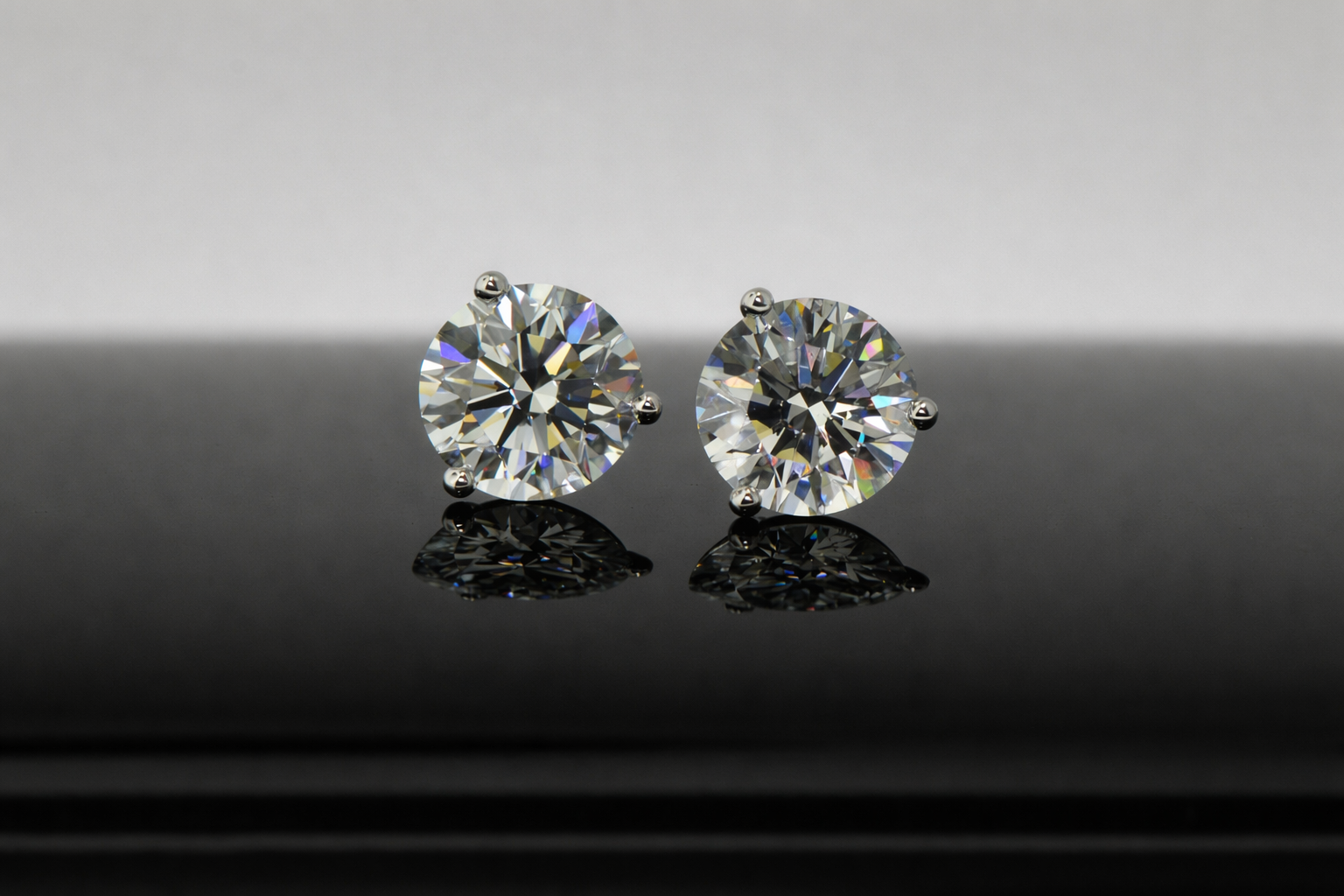 Two diamond studs displayed on glass