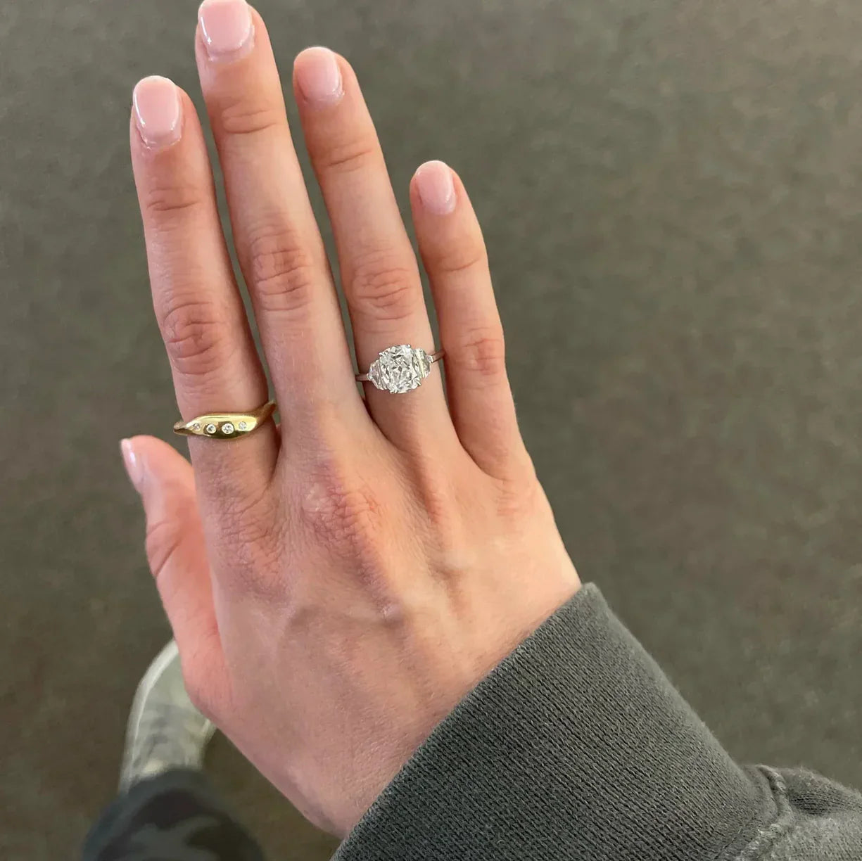Person in a sweater sitting in an Adirondack chair drinking coffee with a beautiful silver colored ring on