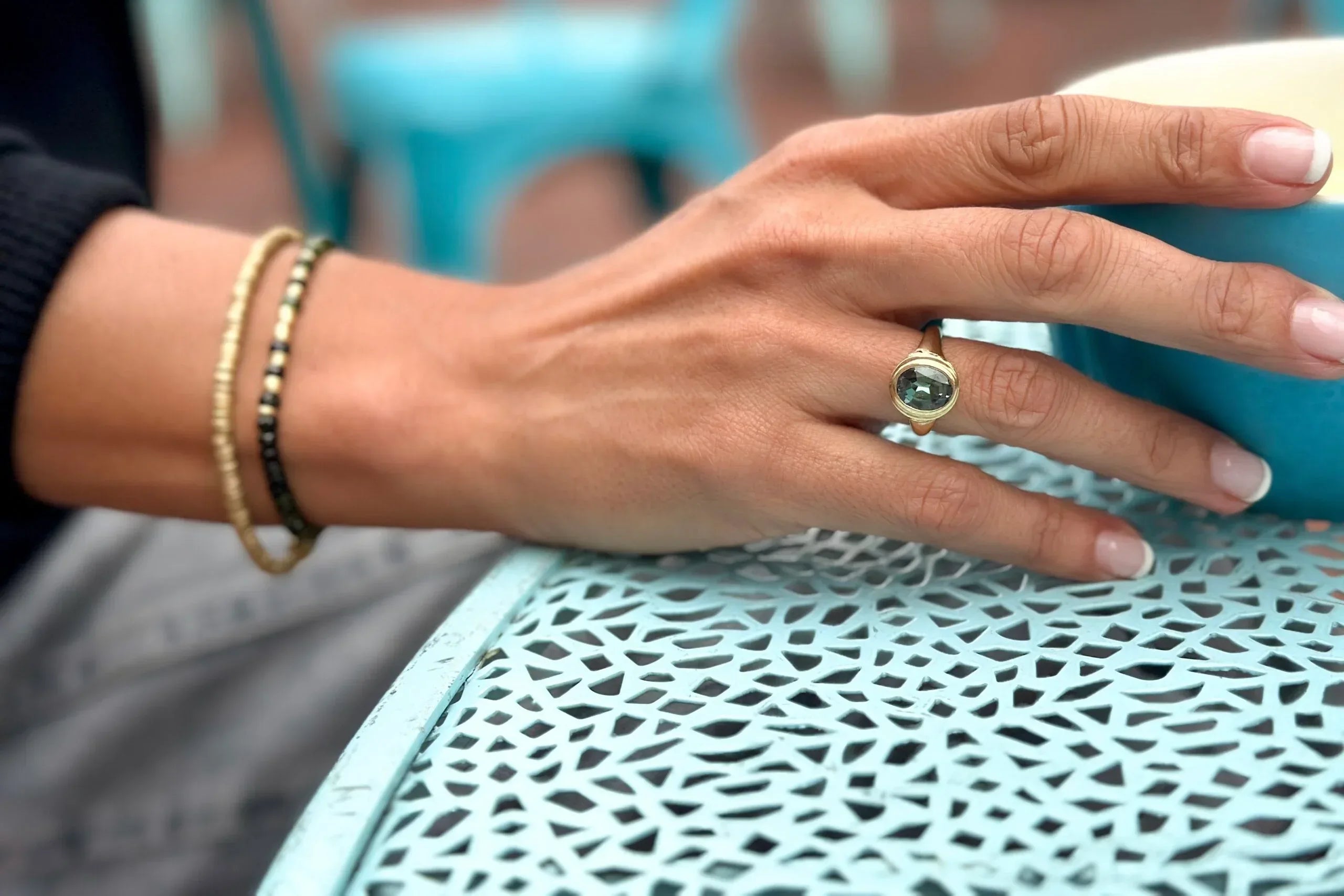 Hand with a ring holding a blue mug on a textured surface
