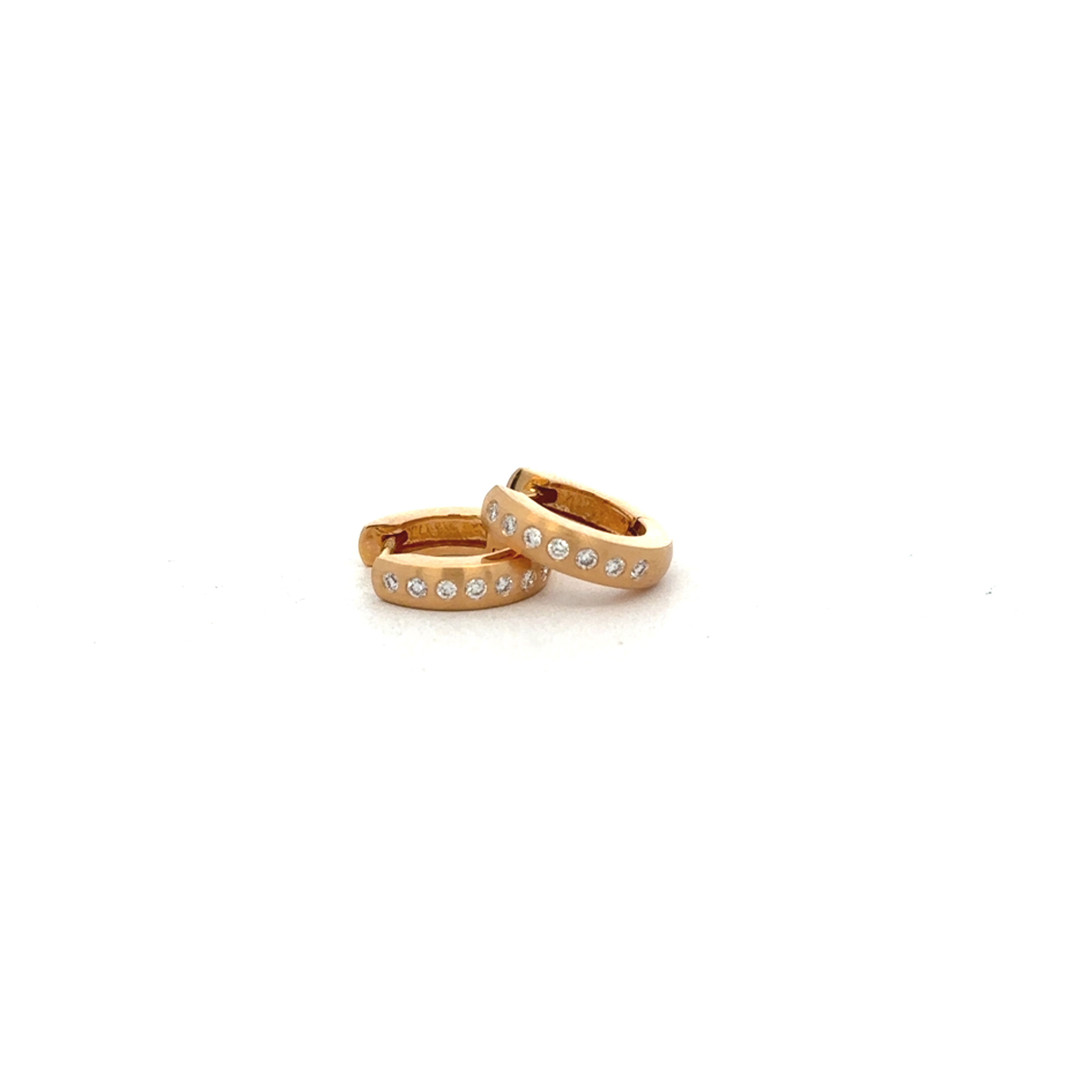 Gold earring swith embedded diamonds on a light gray background