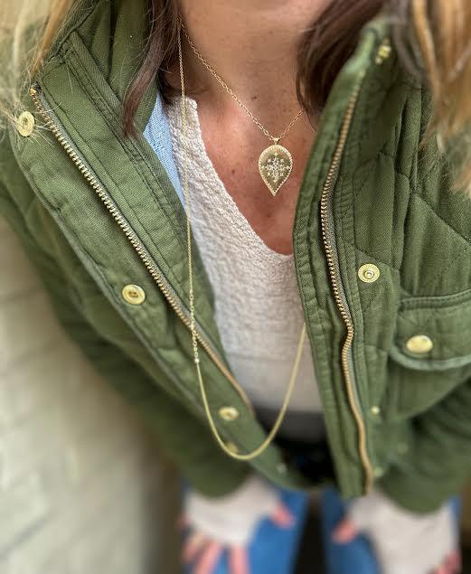 Person wearing a green jacket with gold buttons, white top, and blue pants.