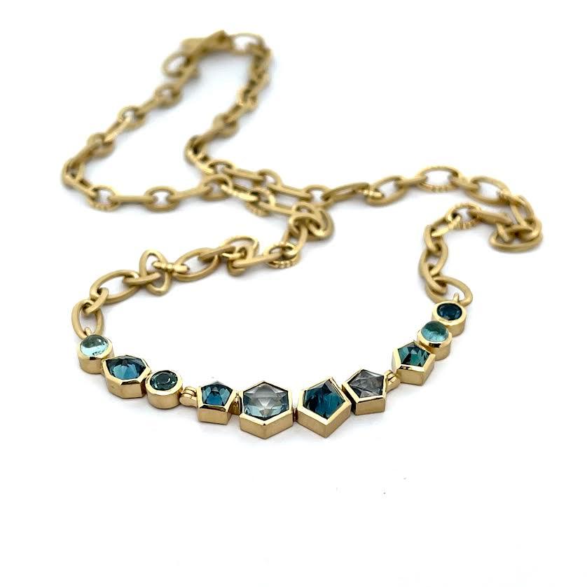Gold necklace with blue gemstones on a white background