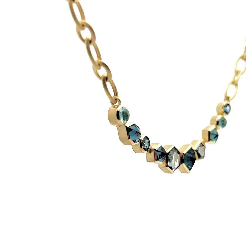 Gold necklace with blue gemstones on a white background