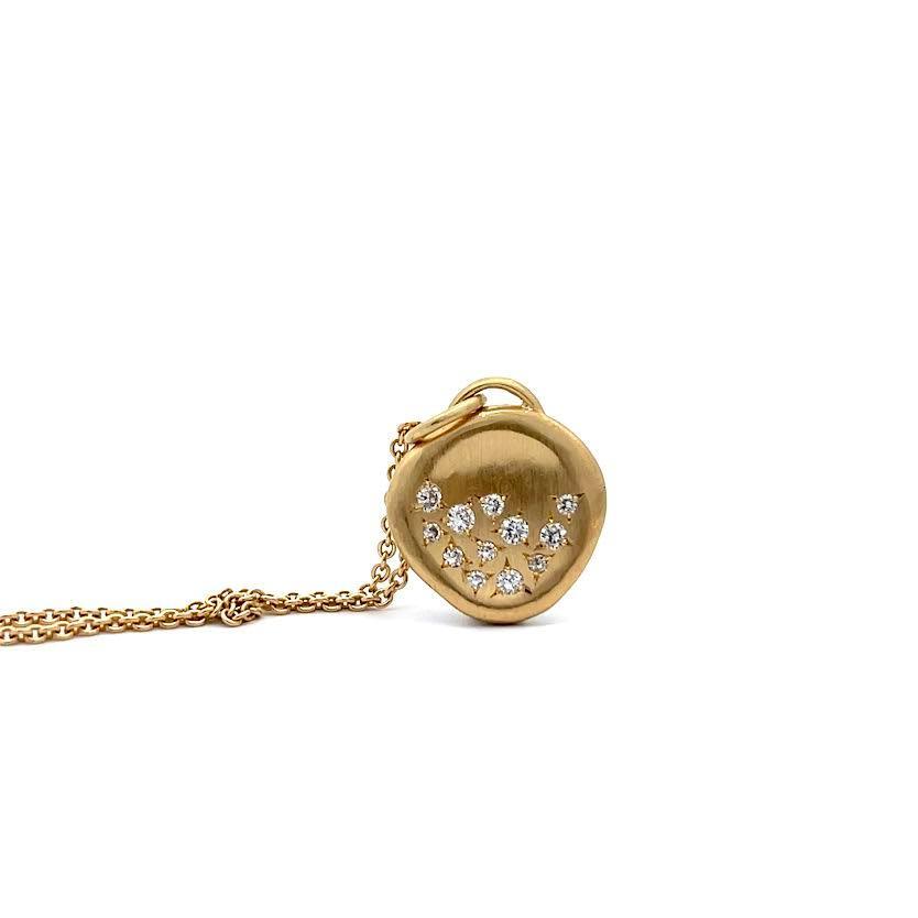 The Ali Dumont Gold and Diamond Half-Full Pendant features a heart-shaped brushed gold design on a gold chain, accented with round brilliant cut diamonds in a crescent pattern on the front.
