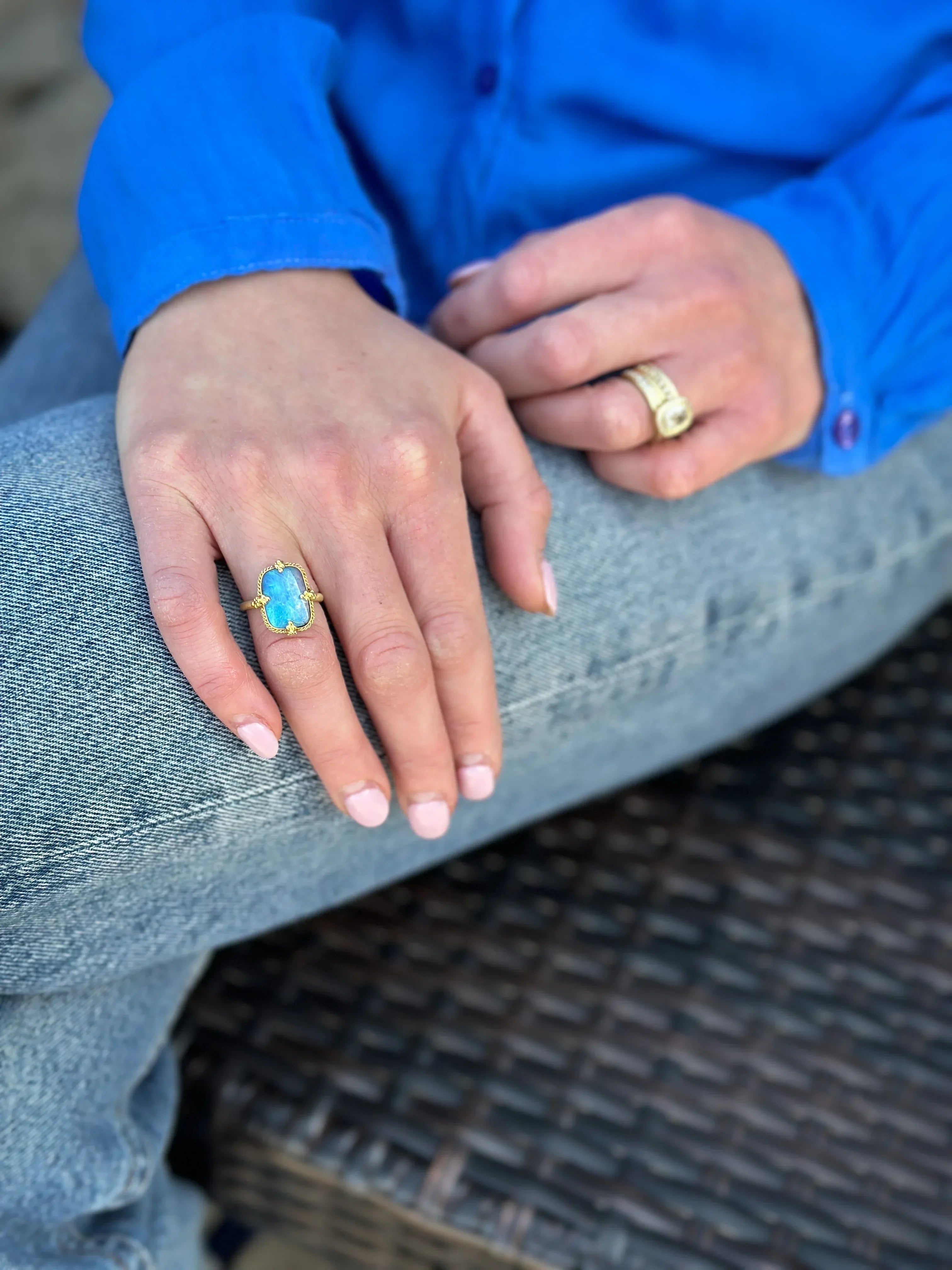 Close-up of hands wearing rings with blue gemstones and gold bands.