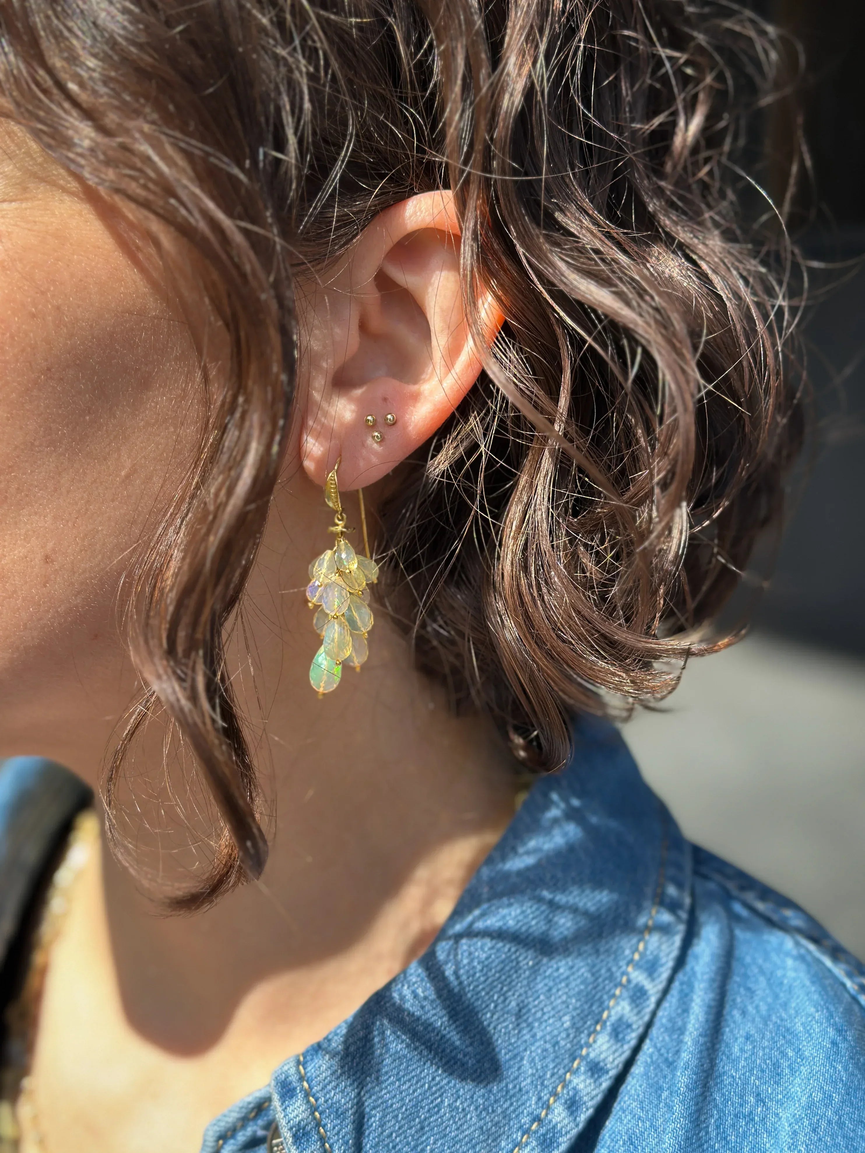 Woman in a jean jacket wearing dangling earring and studs