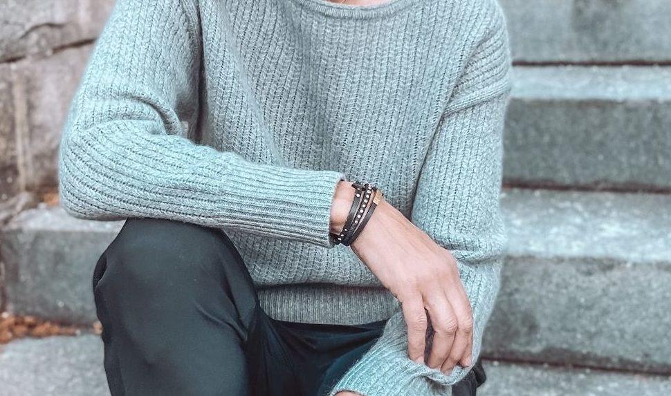 Person wearing a light green sweater sitting on steps.