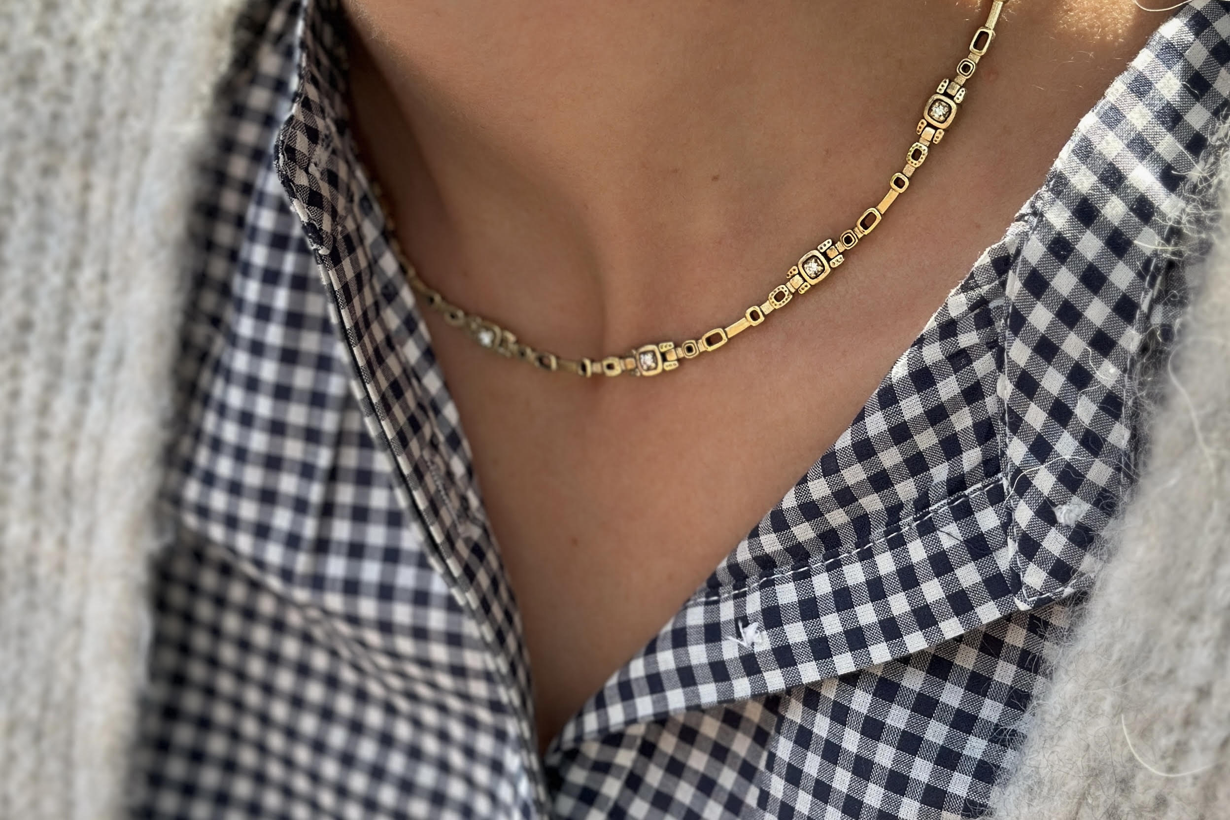 Gold necklace worn by a person wearing a checkered shirt