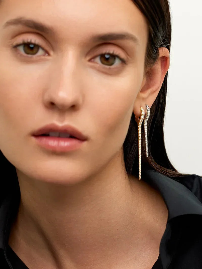 Close-up of a woman wearing gold earrings with a neutral background