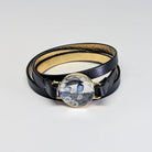 Black leather bracelet with a large crystal charm on a light gray background