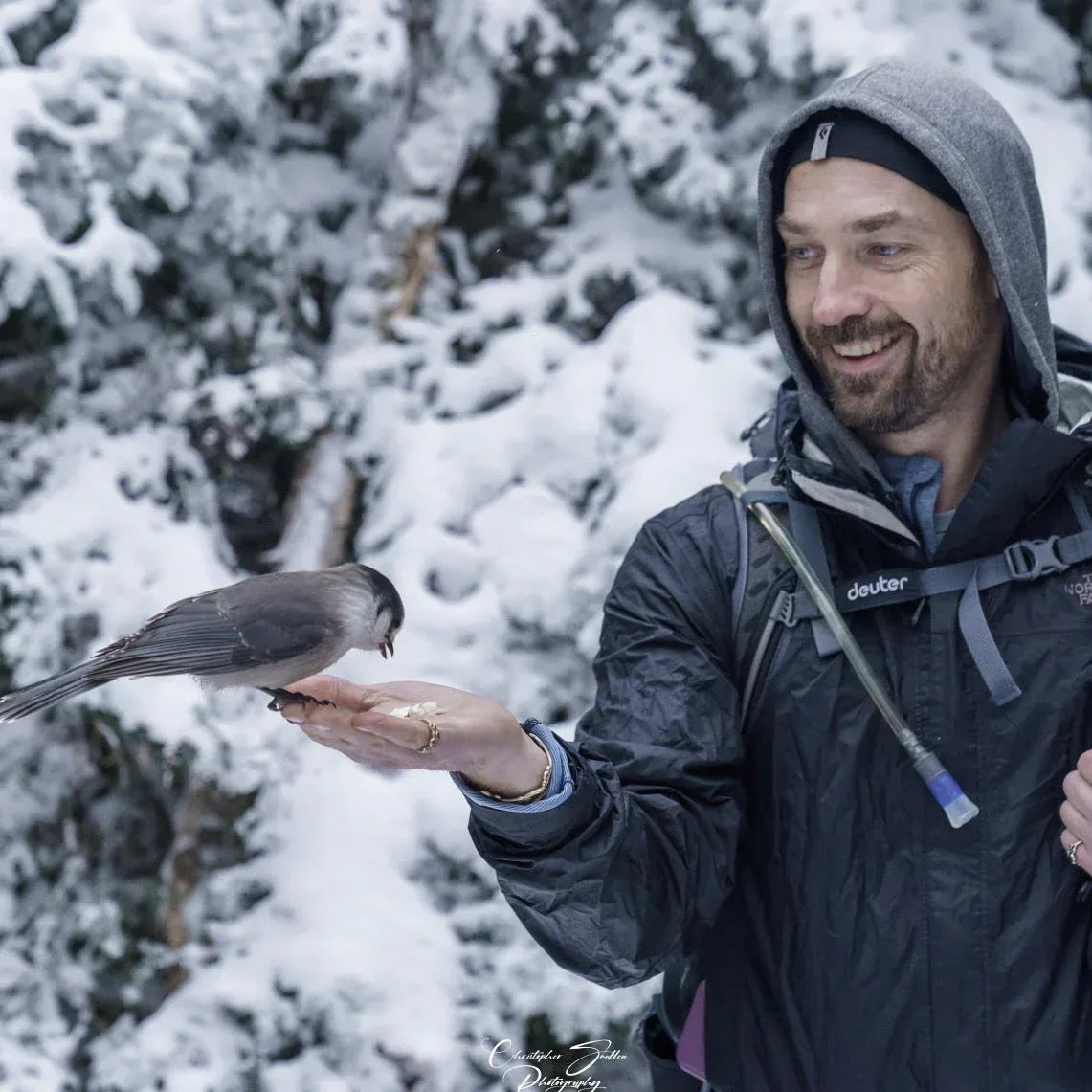 Man feeding a bird in a snowy forest