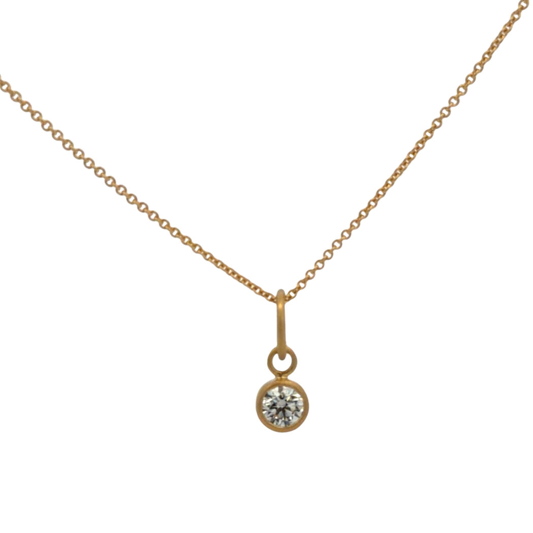 Gold necklace with a diamond pendant on a white background