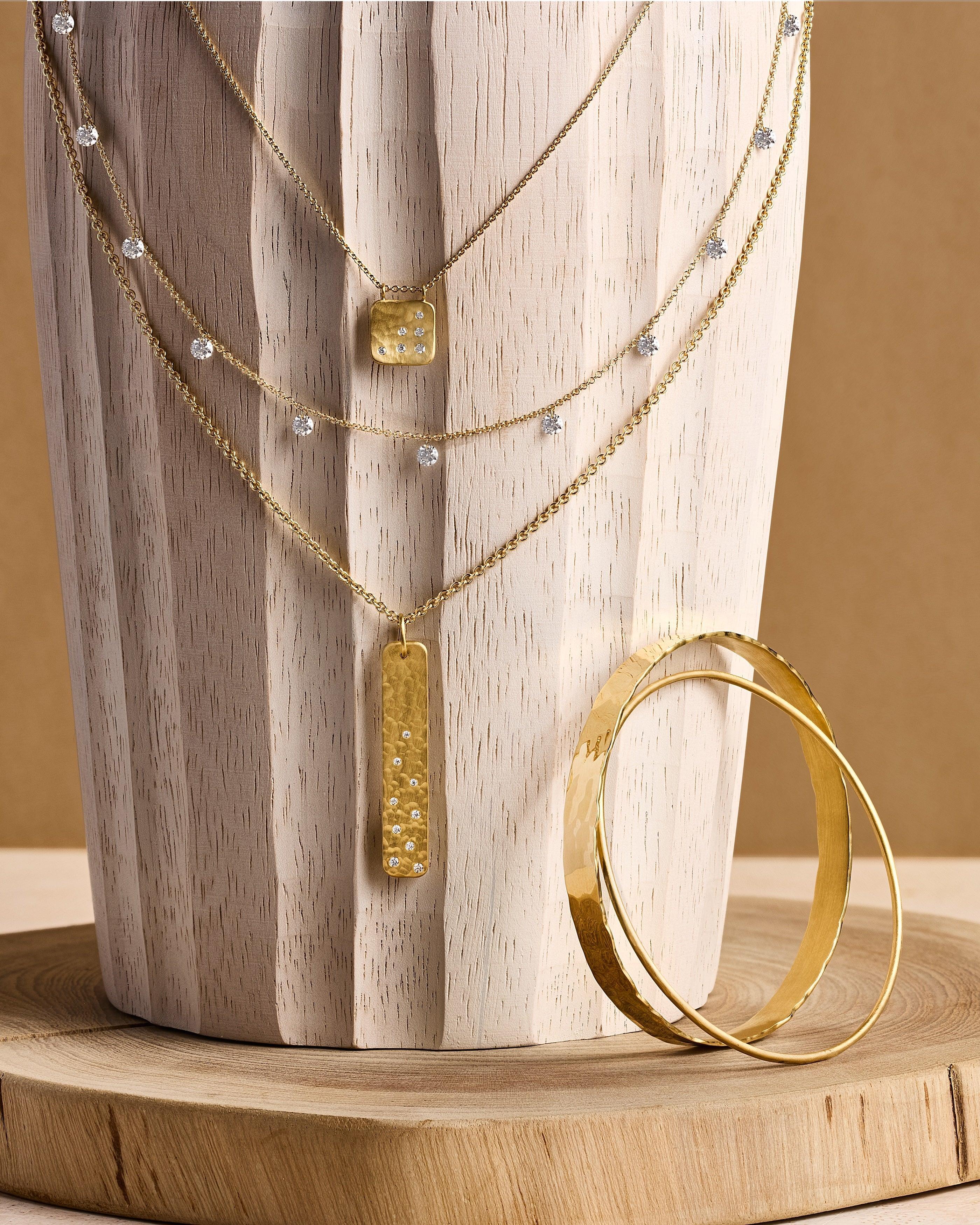 Gold necklace with a pendant and bracelet on a wooden surface