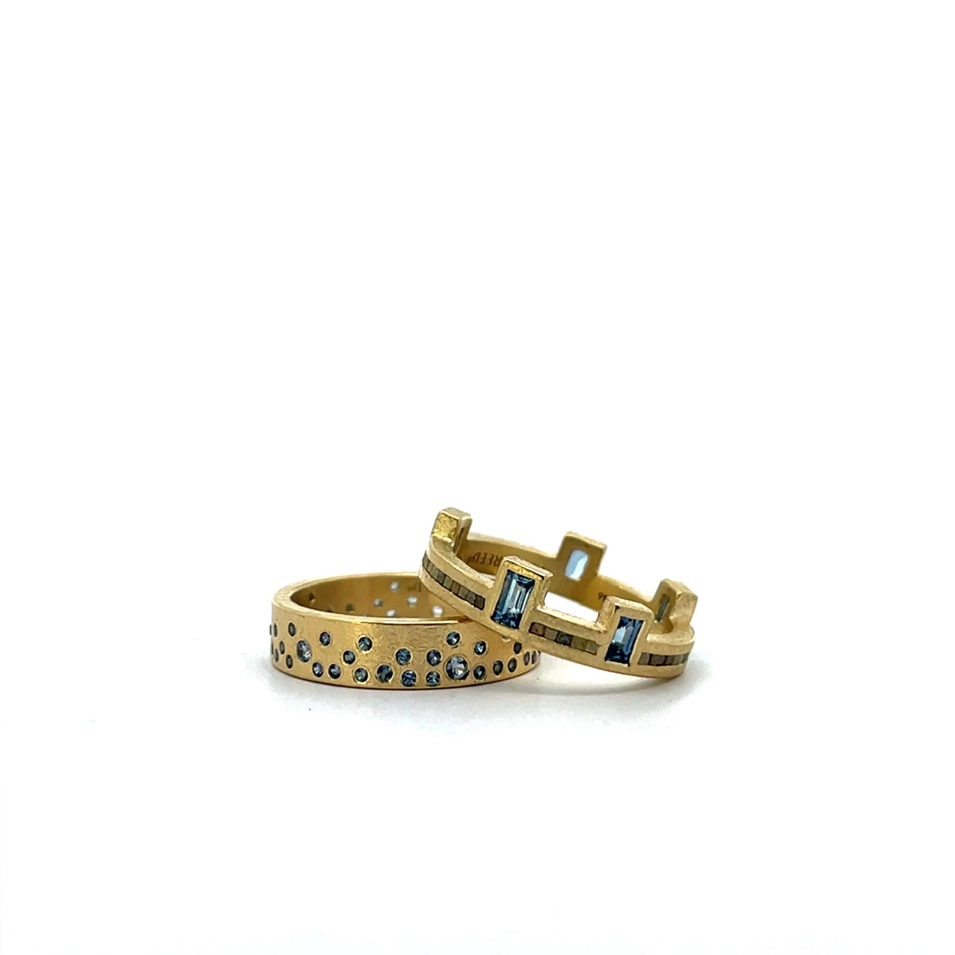 Two gold rings with blue gemstone accents, displayed on a clean white background.