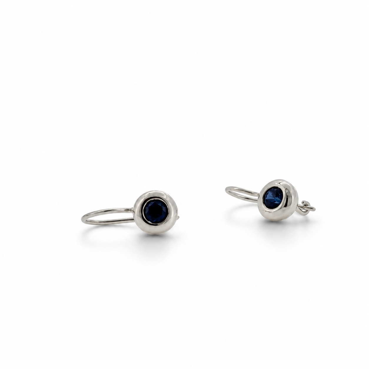 A pair of silver-toned hoop earrings with round bezel-set dark blue gemstones, displayed on a clean white background.