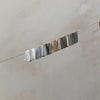 Video of a silver chain with different colored flat charms that shimmer in the light.